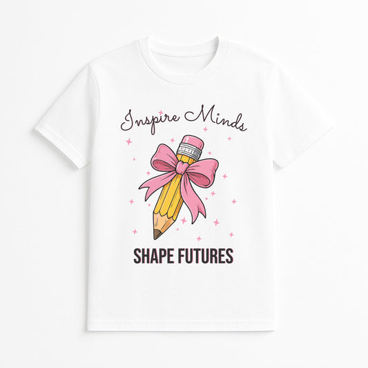White t-shirt with a pencil and bow design and text 'Inspire Minds Shape Futures' on a white background