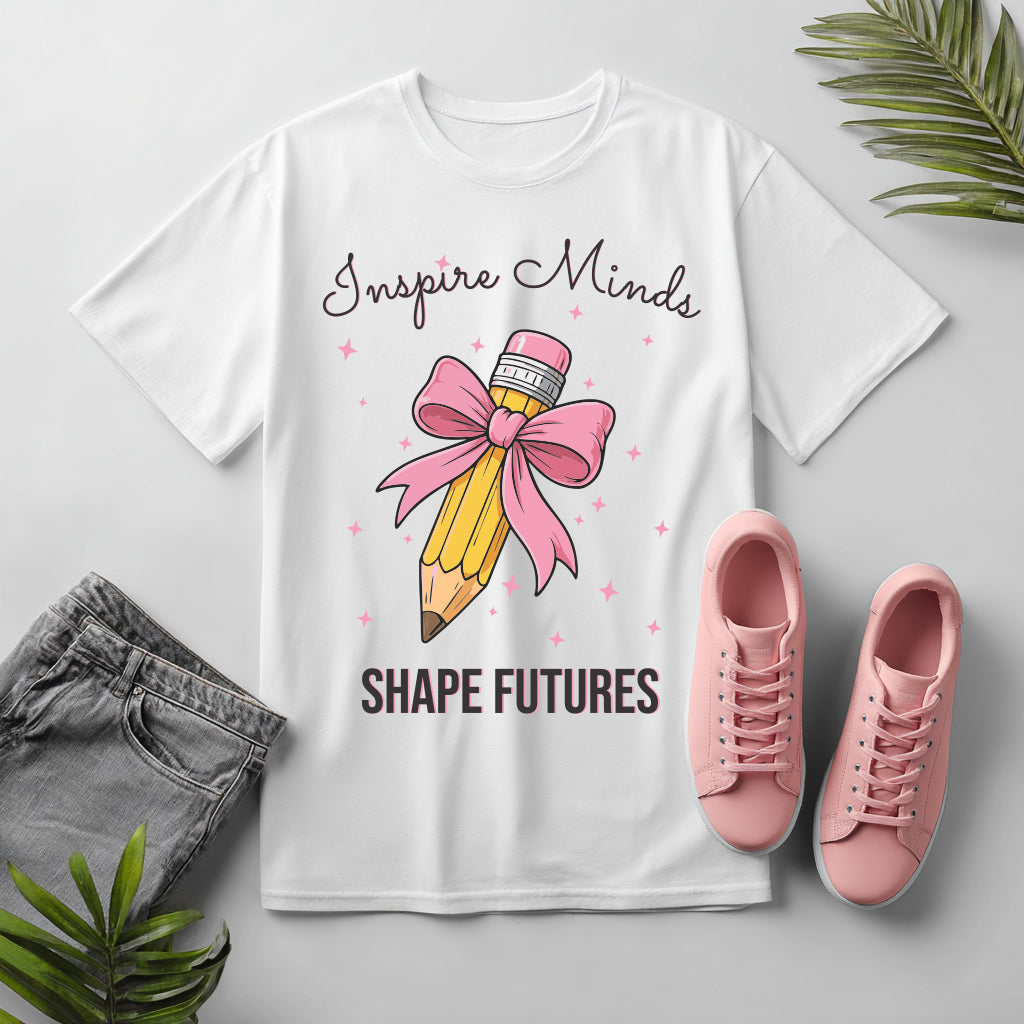 White t-shirt with a pencil and bow graphic, pink shoes, and gray pants on a light gray background.