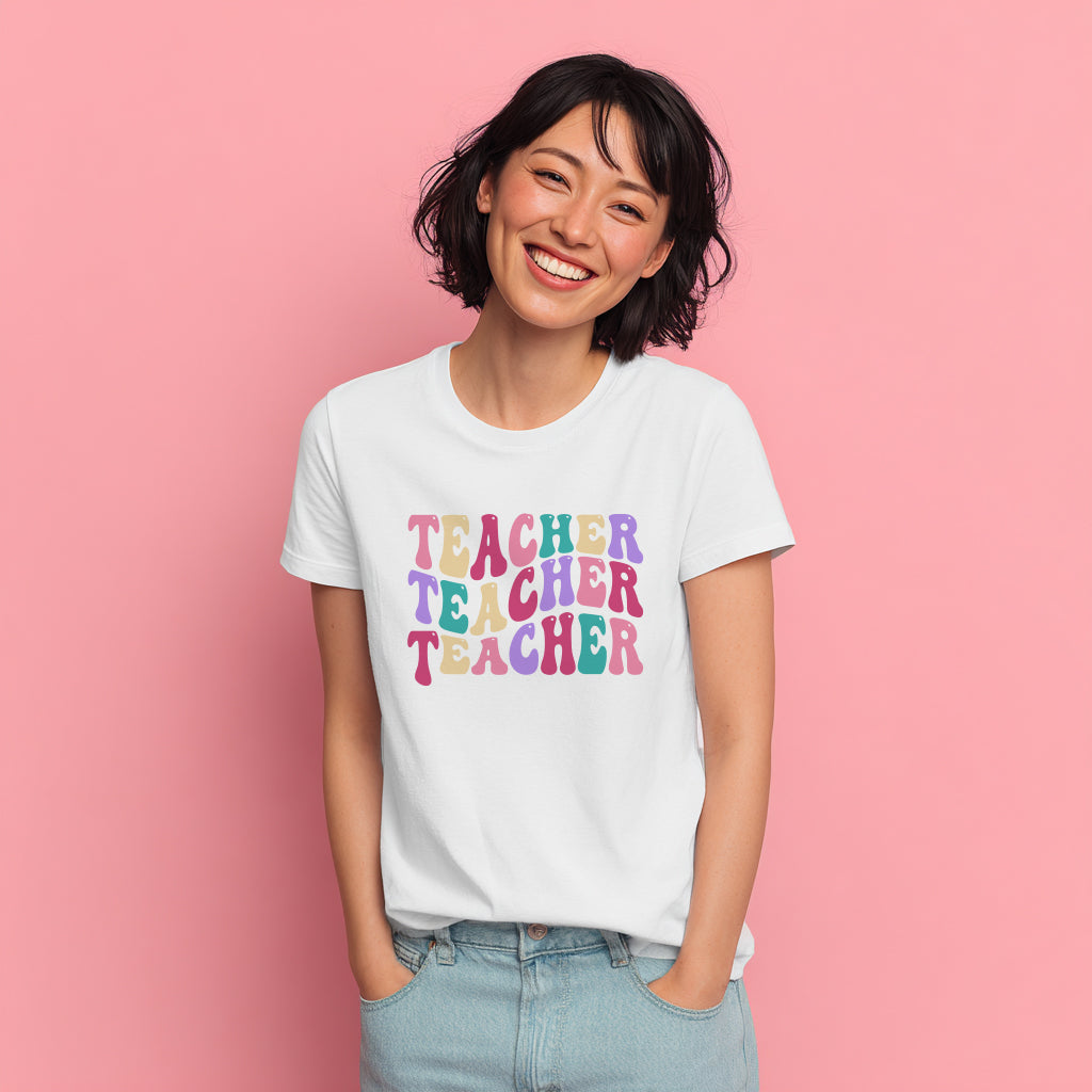 Person wearing a white t-shirt with 'TEACHER TEACHER TEACHER' text in colorful letters on a pink background
