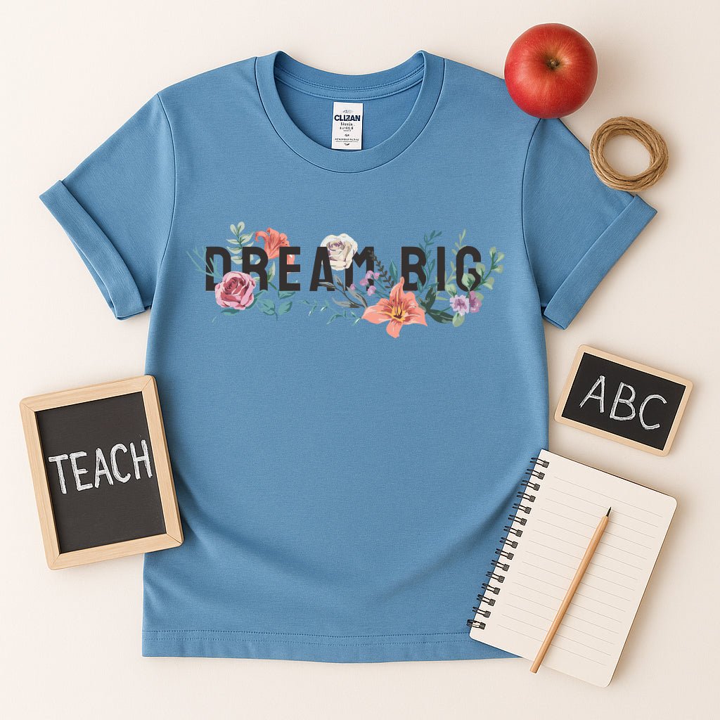 Dream Big teacher t-shirt in Blue with floral graphic, inspirational classroom shirt styled with apple, chalkboards, and notebook, perfect back to school tee