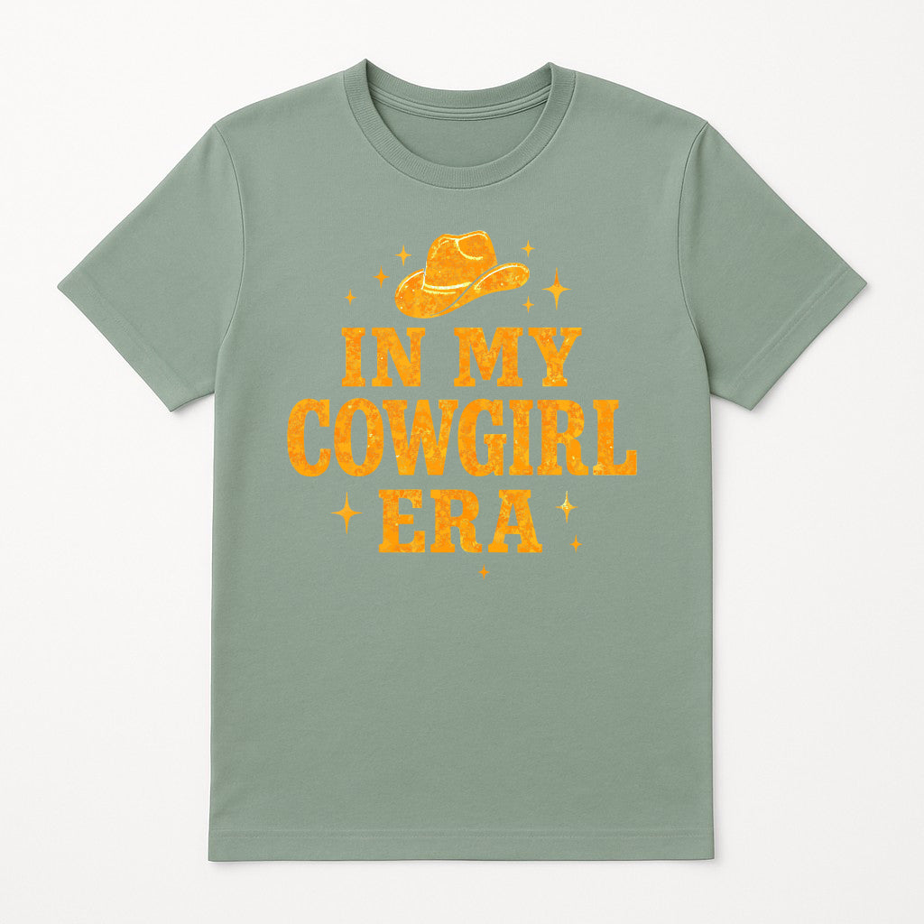 In My Cowgirl Era graphic t-shirt in sage green, Western country music inspired tee with bold distressed lettering and cowboy hat design, trendy cowgirl aesthetic shirt for women