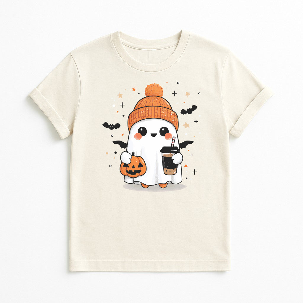 A cream-colored short-sleeve t-shirt featuring a cute cartoon graphic of a ghost character wearing an orange beanie, holding a jack-o'-lantern and a drink, with small bats and stars.