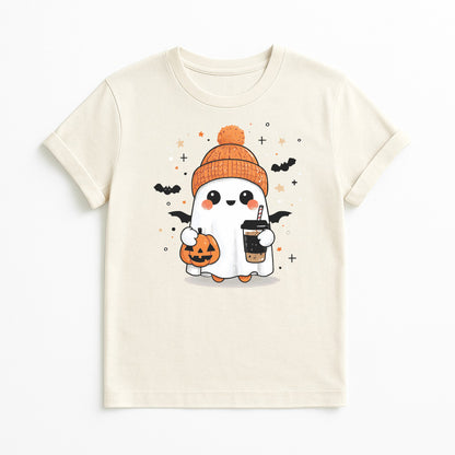 A cream-colored short-sleeve t-shirt featuring a cute cartoon graphic of a ghost character wearing an orange beanie, holding a jack-o'-lantern and a drink, with small bats and stars.