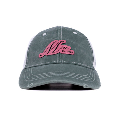 Front view of Mom Est. 2025 trucker hat in sage green with rose pink leather patch