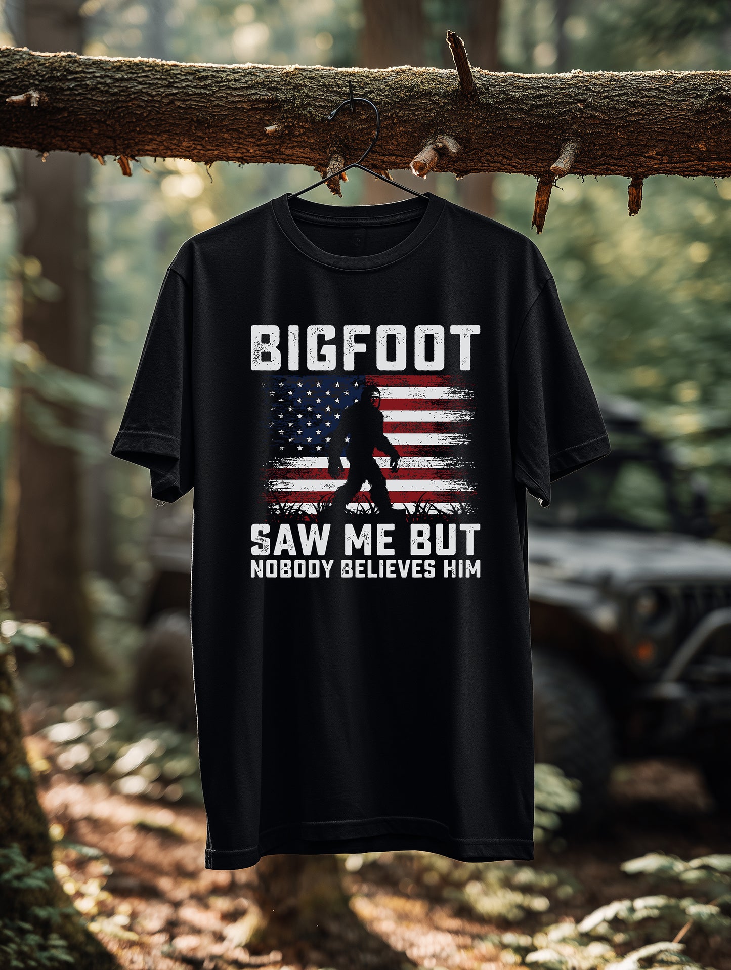 Black Bigfoot patriotic graphic tee hanging outdoors in forest setting