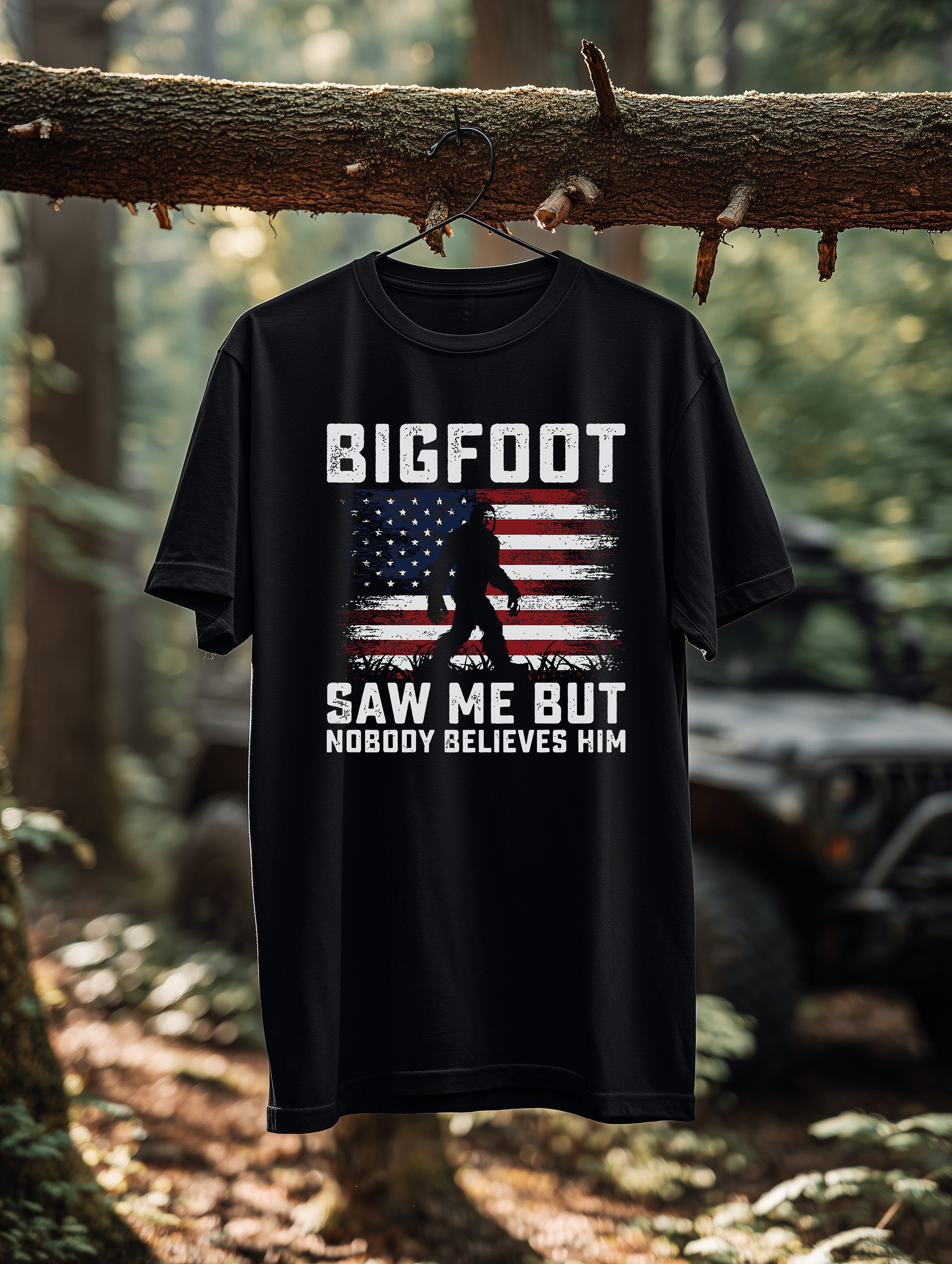 Black Bigfoot patriotic graphic tee hanging outdoors in forest setting