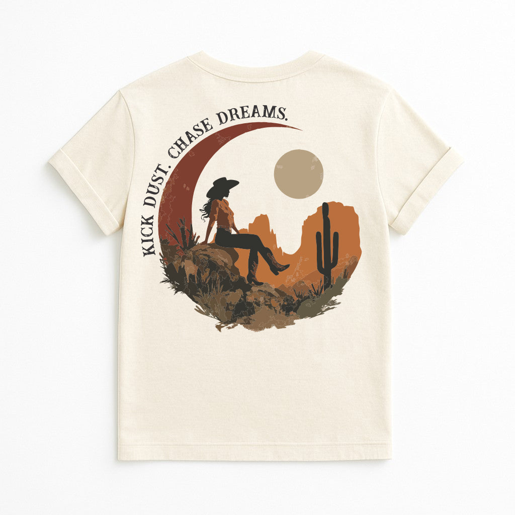 Kick Dust Chase Dreams graphic t-shirt in bone color, Western cowgirl desert scene with moon and cactus, inspirational country tee for women